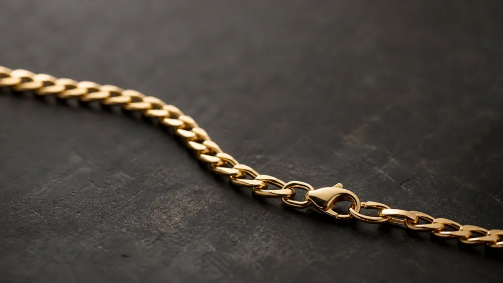 Gold chain and clasp inspected on a dark jeweler's bench